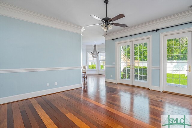 unfurnished room with ceiling fan with notable chandelier, french doors, ornamental molding, and dark wood-type flooring