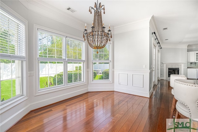 dining space featuring a fireplace, a notable chandelier, ornamental molding, dark hardwood / wood-style floors, and a barn door