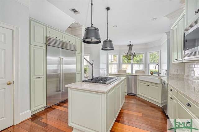 kitchen with built in appliances, sink, a center island, and light hardwood / wood-style flooring