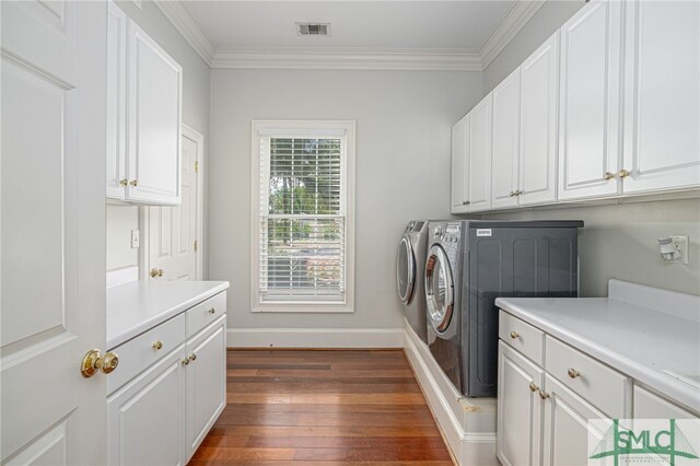 laundry room featuring crown molding, dark hardwood / wood-style flooring, cabinets, and separate washer and dryer