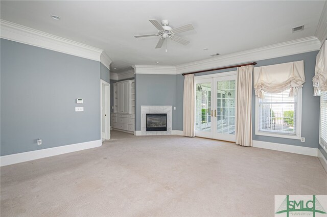 unfurnished living room featuring a high end fireplace, crown molding, ceiling fan, and carpet floors