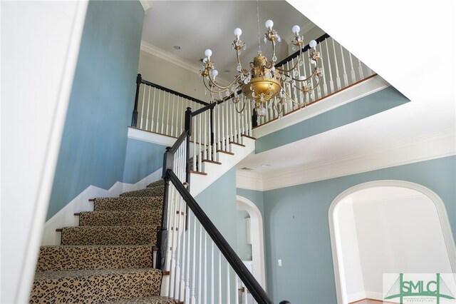 staircase with ornamental molding and a chandelier