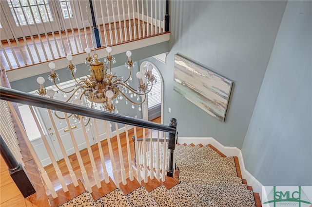 stairway featuring hardwood / wood-style flooring and an inviting chandelier