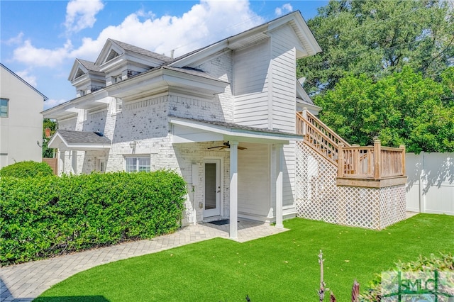 exterior space with a yard, ceiling fan, and a deck