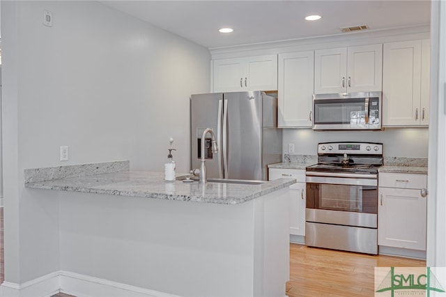 kitchen featuring white cabinetry, kitchen peninsula, stainless steel appliances, and light hardwood / wood-style floors