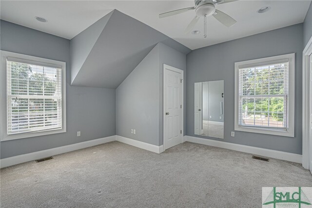 additional living space featuring light carpet, lofted ceiling, plenty of natural light, and ceiling fan