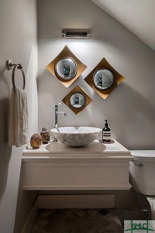 bathroom with vaulted ceiling, toilet, and vanity