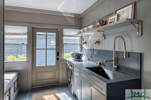 kitchen featuring ornamental molding, dark tile patterned floors, sink, and washer / clothes dryer