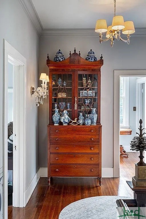 living area featuring ornamental molding, dark hardwood / wood-style flooring, and a notable chandelier