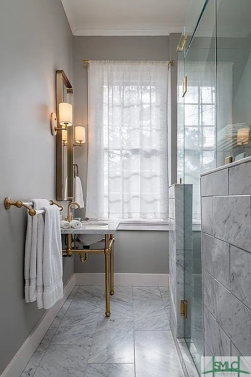 bathroom with a shower with door and ornamental molding