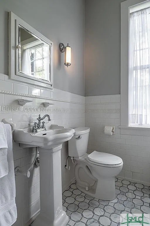 bathroom with a healthy amount of sunlight, toilet, and tile patterned floors