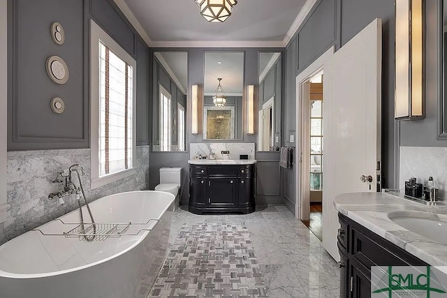 bathroom with a tub, a healthy amount of sunlight, vanity, and toilet