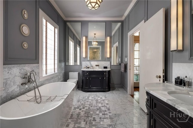 56 E 54th St, Savannah, GA 31405 - bathroom with plenty of natural light, two vanities, a soaking tub, crown molding, and tasteful backsplash