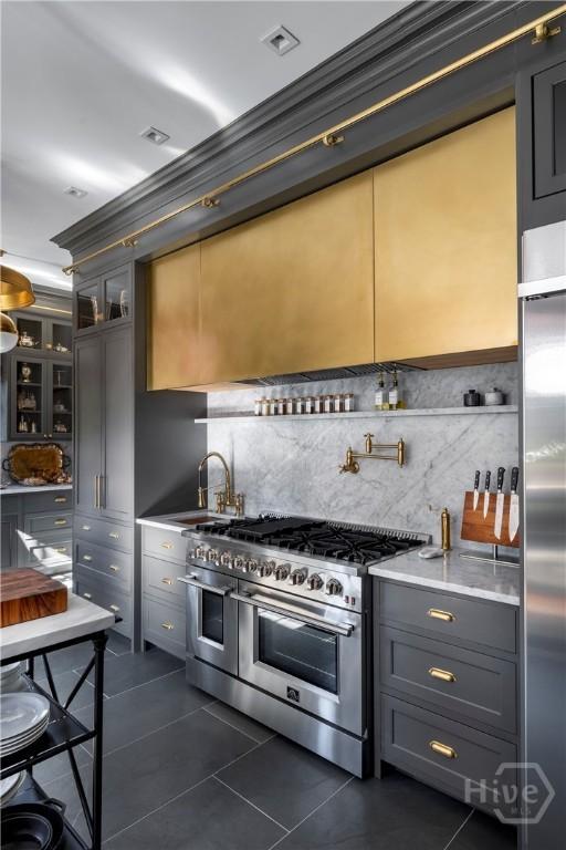 56 E 54th St, Savannah, GA 31405 - kitchen with premium appliances, dark tile patterned floors, decorative backsplash, glass insert cabinets, and light countertops