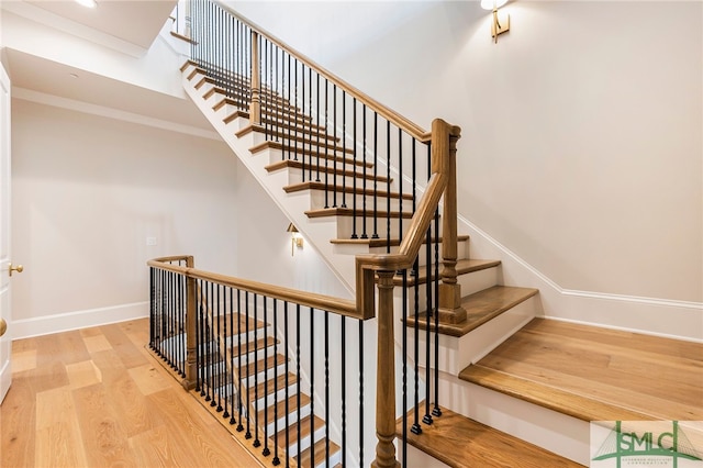 stairs featuring ornamental molding and wood-type flooring