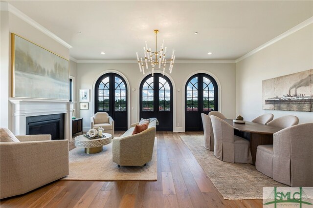 living room featuring light hardwood / wood-style flooring, ornamental molding, and a chandelier