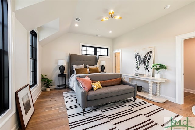 bedroom with lofted ceiling, a notable chandelier, and light hardwood / wood-style floors