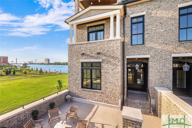 view of front of property with a water view, a front lawn, and french doors