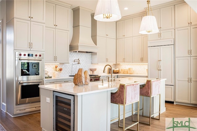 kitchen featuring custom exhaust hood, wood-type flooring, paneled built in fridge, beverage cooler, and double oven