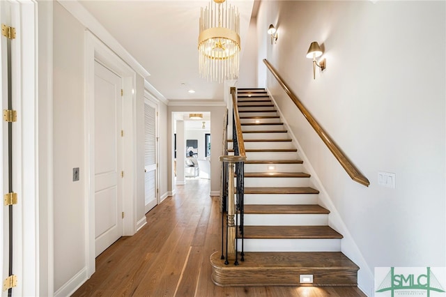 staircase with an inviting chandelier and wood-type flooring