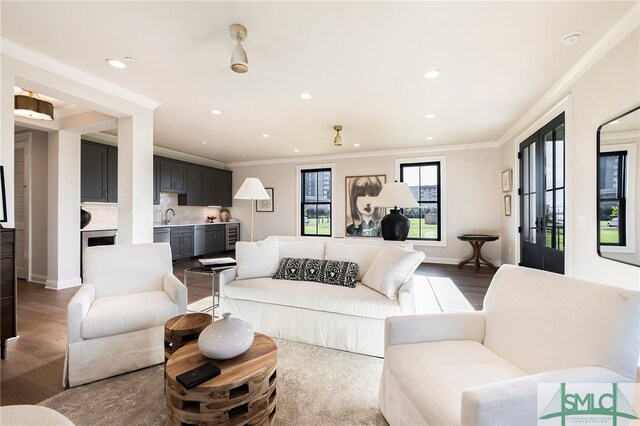 living room featuring crown molding, wood-type flooring, and sink