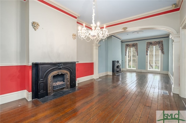 unfurnished living room with a chandelier, a wood stove, dark hardwood / wood-style flooring, and crown molding