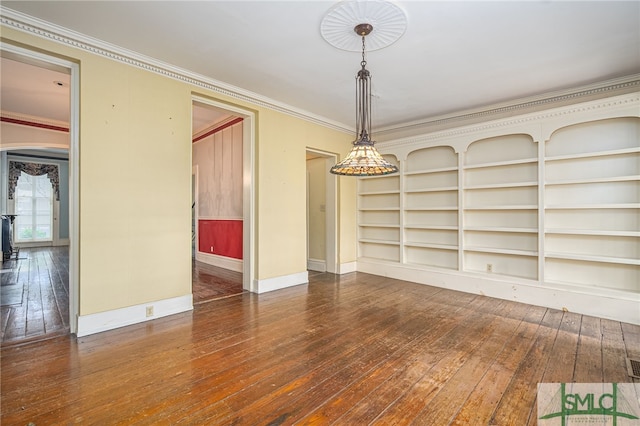 empty room featuring dark wood-type flooring, built in features, and crown molding