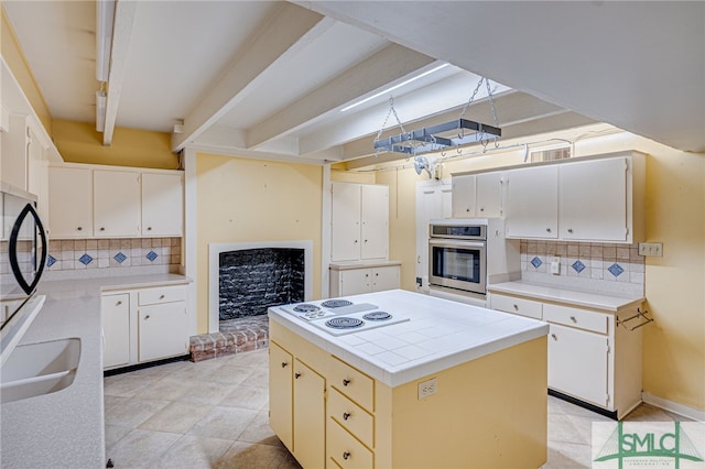 kitchen with white cabinets, white electric stovetop, a center island, and stainless steel oven