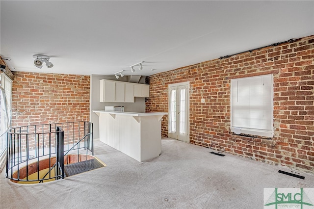 115 W Gordon St, Savannah, GA 31401 - kitchen with a peninsula, white cabinets, brick wall, light carpet, and light countertops