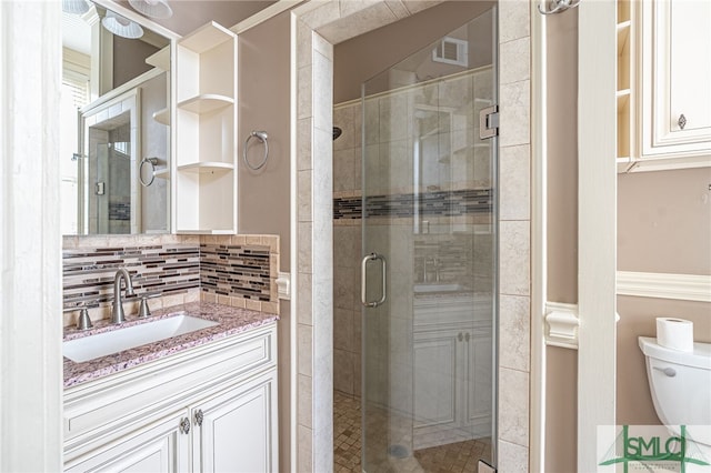 bathroom featuring vanity, toilet, walk in shower, and decorative backsplash