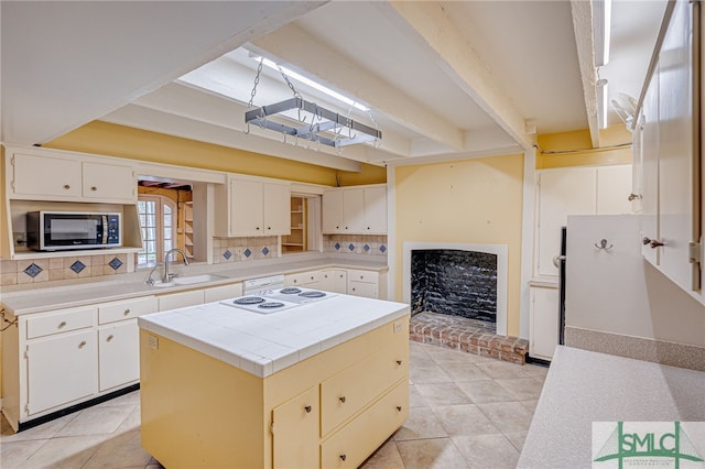 kitchen featuring tasteful backsplash, a kitchen island, light tile patterned floors, and white cabinets