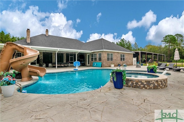 view of pool with an in ground hot tub, a patio area, and a water slide