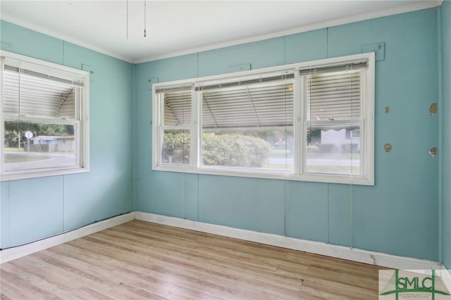 spare room featuring crown molding and light hardwood / wood-style floors