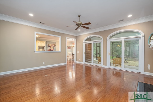 unfurnished room featuring crown molding, light hardwood / wood-style flooring, and ceiling fan with notable chandelier