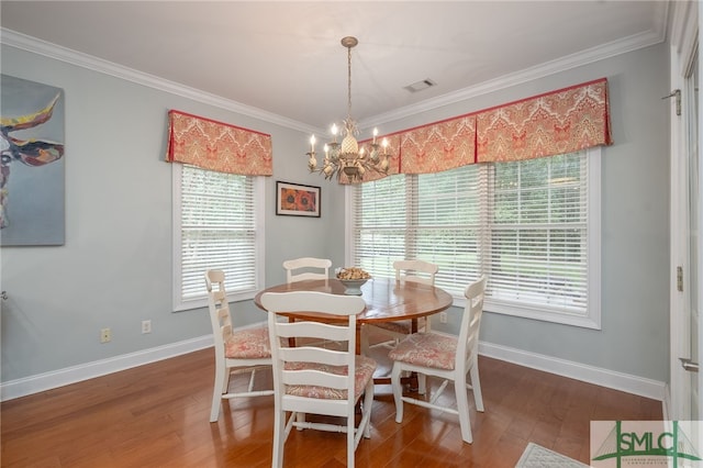 dining room with hardwood / wood-style floors, ornamental molding, and a notable chandelier