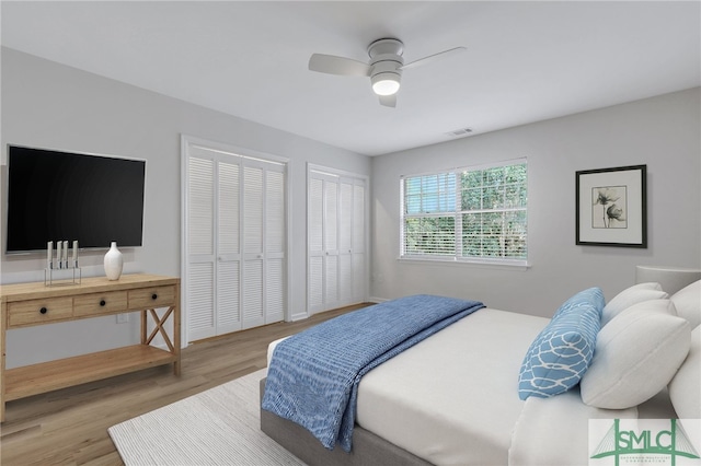 bedroom with ceiling fan, two closets, and hardwood / wood-style floors