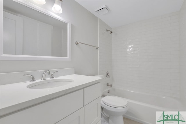 full bathroom with tiled shower / bath, vanity, and toilet