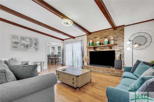 living room featuring vaulted ceiling with beams, a fireplace, and light hardwood / wood-style flooring