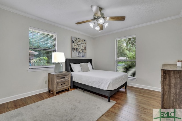 bedroom featuring ceiling fan, ornamental molding, hardwood / wood-style floors, and multiple windows