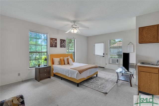 bedroom featuring ceiling fan, cooling unit, a textured ceiling, and multiple windows