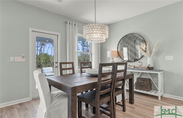 dining area with light hardwood / wood-style flooring and a notable chandelier