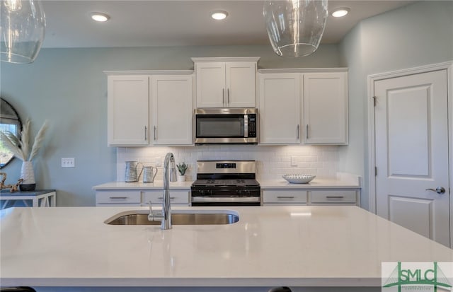 kitchen with stainless steel appliances, white cabinets, tasteful backsplash, and sink