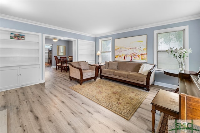 living room with built in shelves, light hardwood / wood-style flooring, ornamental molding, and a healthy amount of sunlight