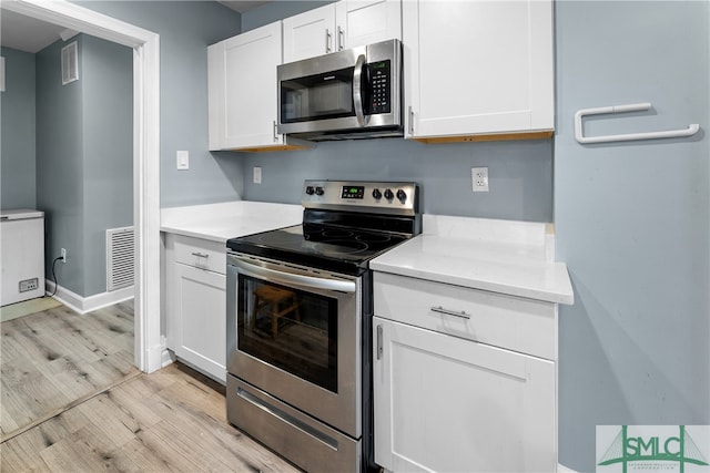 kitchen with white cabinets, appliances with stainless steel finishes, and light wood-type flooring