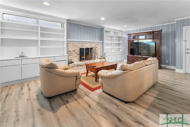 living room with crown molding, light hardwood / wood-style flooring, built in features, and a brick fireplace