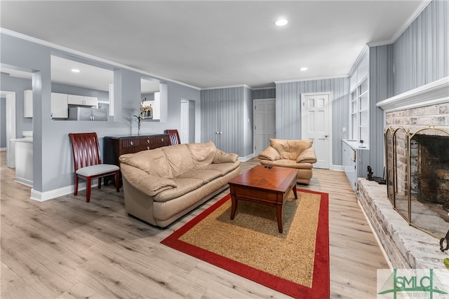 living room featuring a brick fireplace, ornamental molding, and light hardwood / wood-style floors