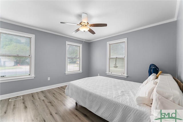 bedroom with crown molding, light hardwood / wood-style floors, and ceiling fan