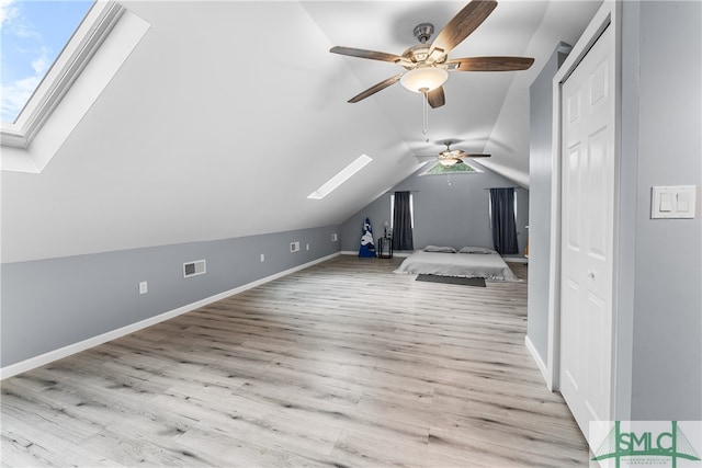 bonus room with light wood-type flooring, vaulted ceiling with skylight, and ceiling fan