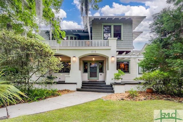 view of front of house featuring a balcony, a front lawn, and covered porch