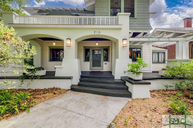 property entrance featuring a balcony and covered porch